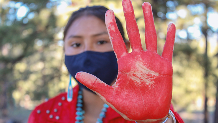 Native girl holds painted hand up to camera. 