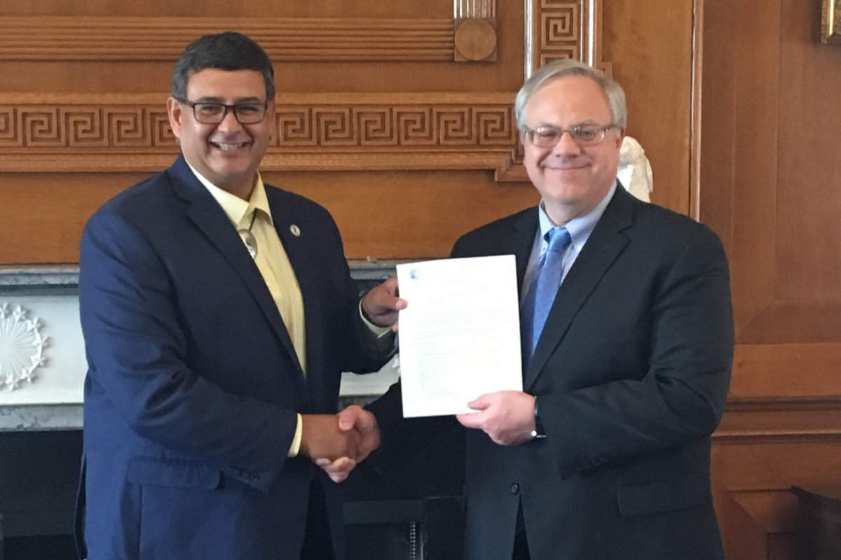 Interior Secretary David Bernhardt and MHA Nation Chairman Mark Fox hold up the approval letter and shake hands