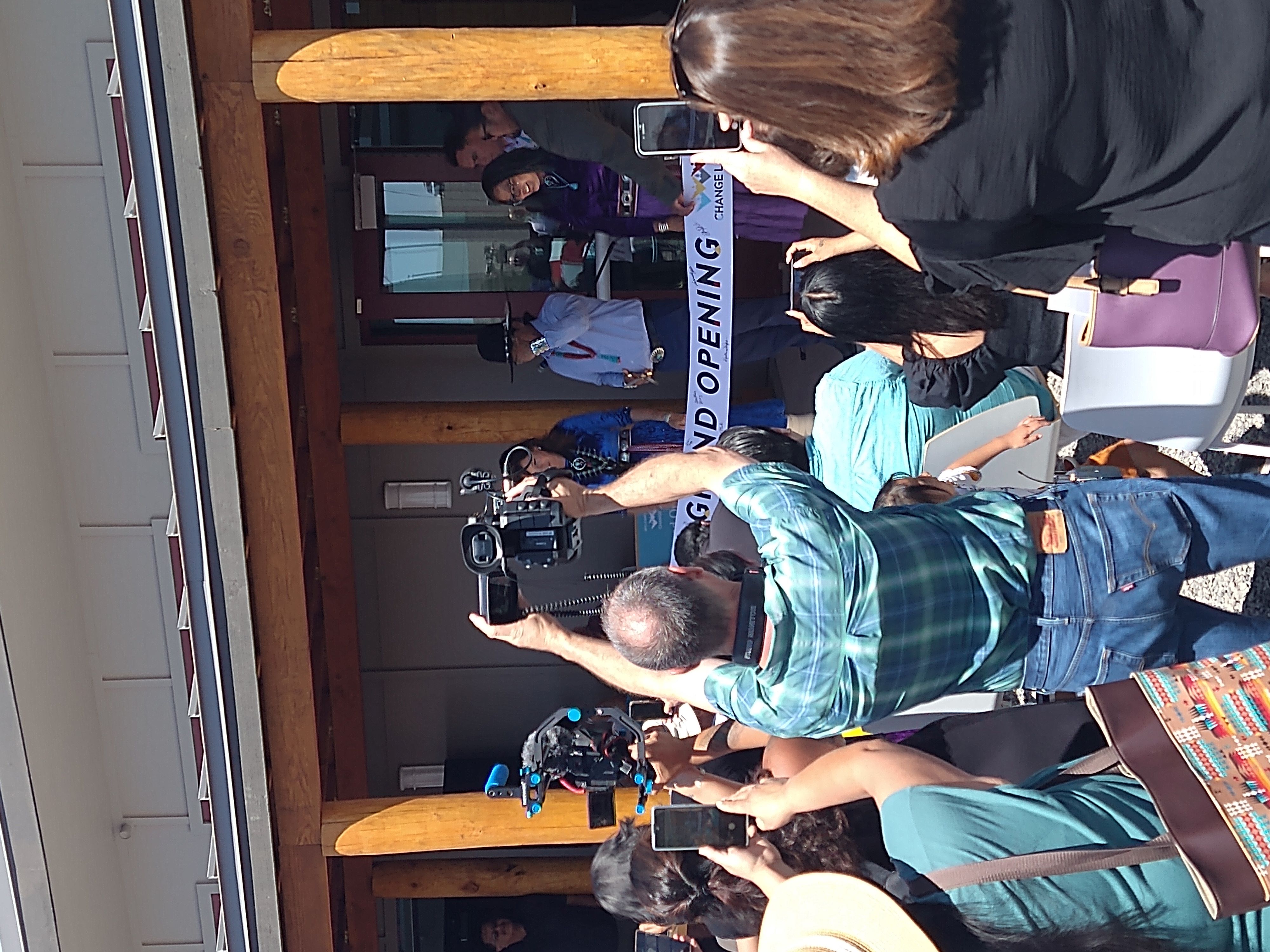 Photographers take pictures of a ribbon cutting.