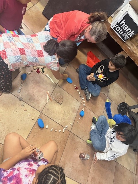 A photo of native youth learning traditional ways of life with a teacher.