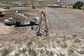 A dump truck delivers rip rock into the 8x8 foot erosion cutoff trench