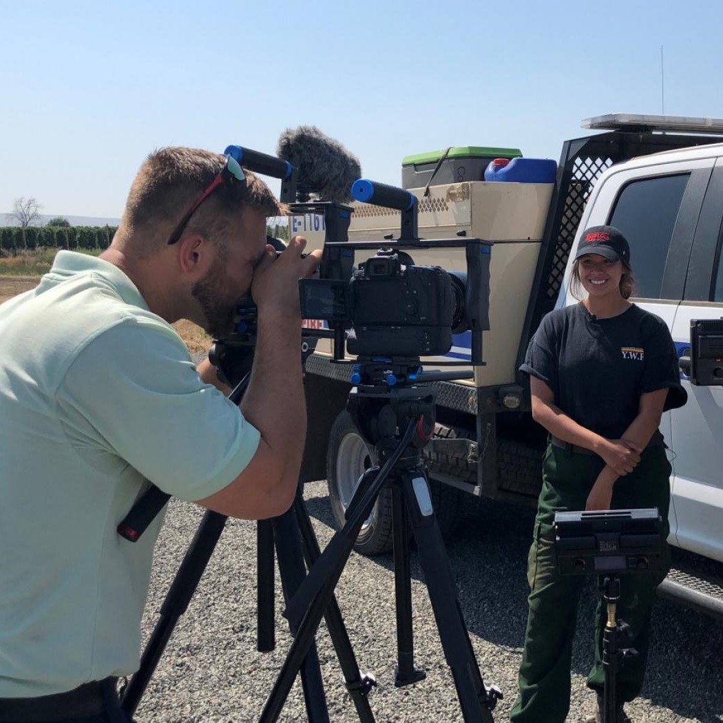 A public affairs employee takes video footage of a firefighter.