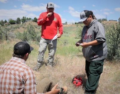 Three Medical Incident Technician training participants take part in a practice medical scenerio outdoors.