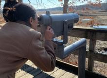 Secretary of the Interior Deb Haaland looking through a tower viewer.