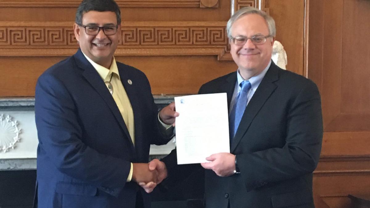 Interior Secretary David Bernhardt and MHA Nation Chairman Mark Fox hold up the approval letter and shake hands