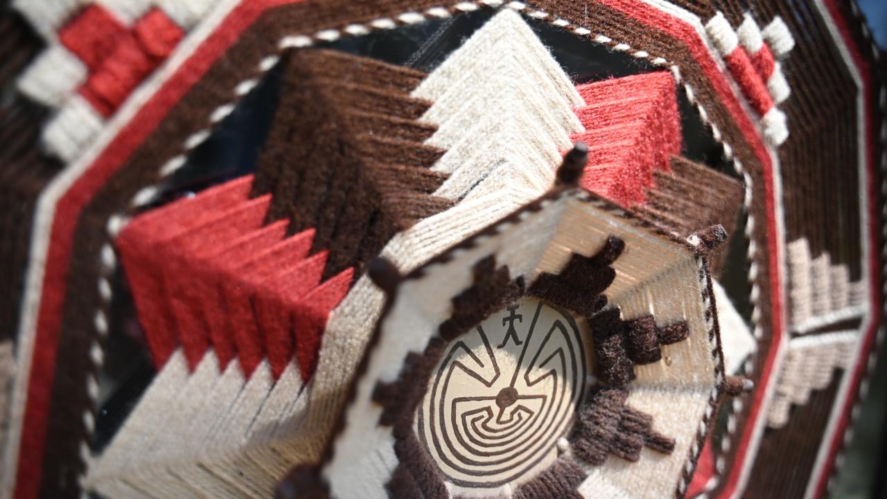 A woven decorative item with a man in the maze design. 