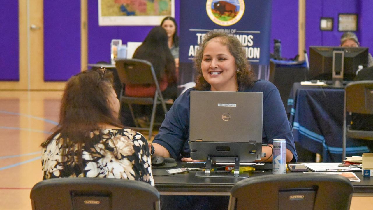 A photo of two women at a table with a computer at the probate outreach event at Gila River Indian Community.