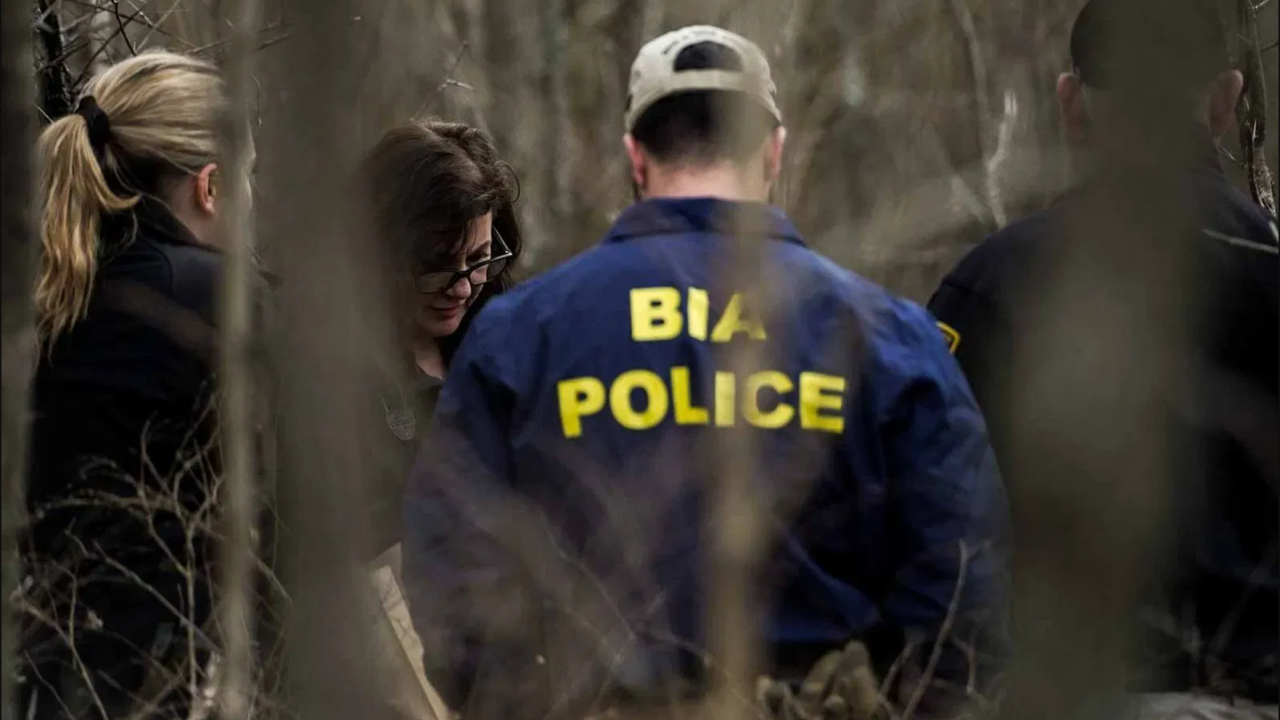 Photo of BIA police seen through the woods investigating a crime scene.
