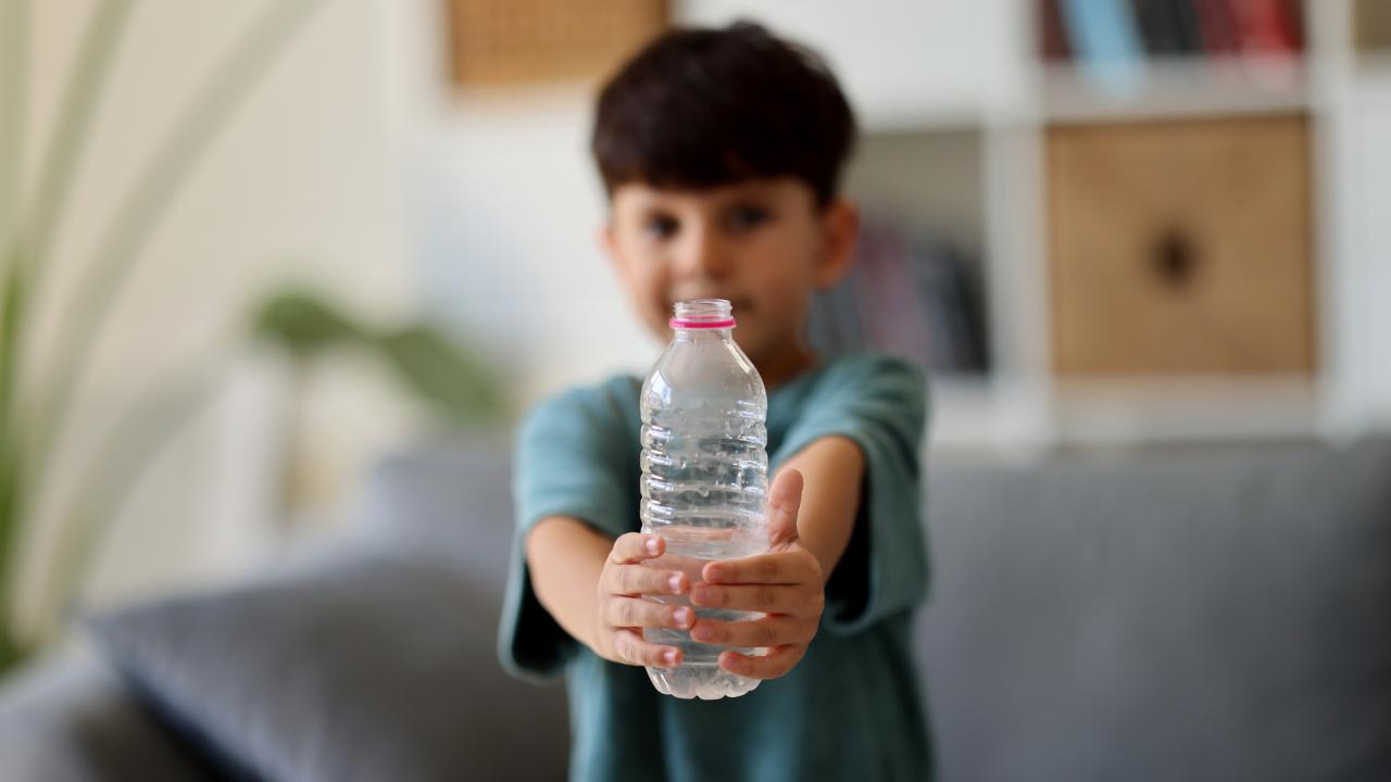 A Native American child holding a bottle of clean drinking water.
