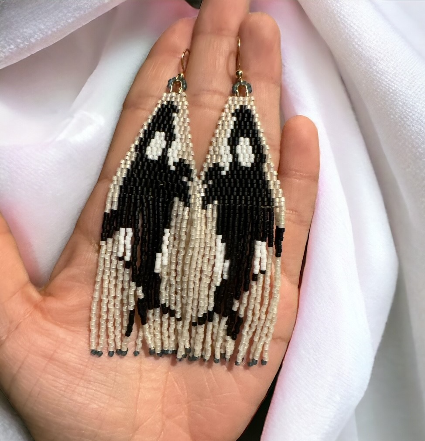 Beadwork earrings each with a profile image of an orca. 