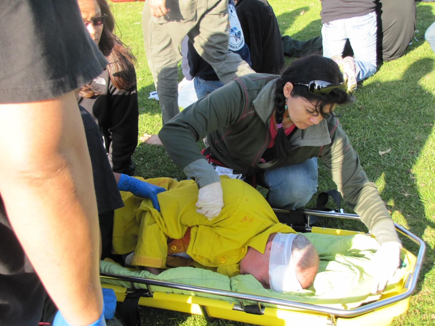 A BIA Wildland Fire First Aid Program trainee checks on a patient during a scenario-based exercise.