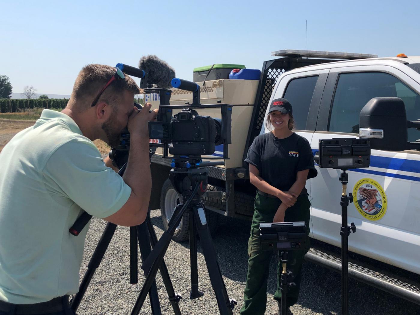 A public information officer takes video footage of a firefighter.