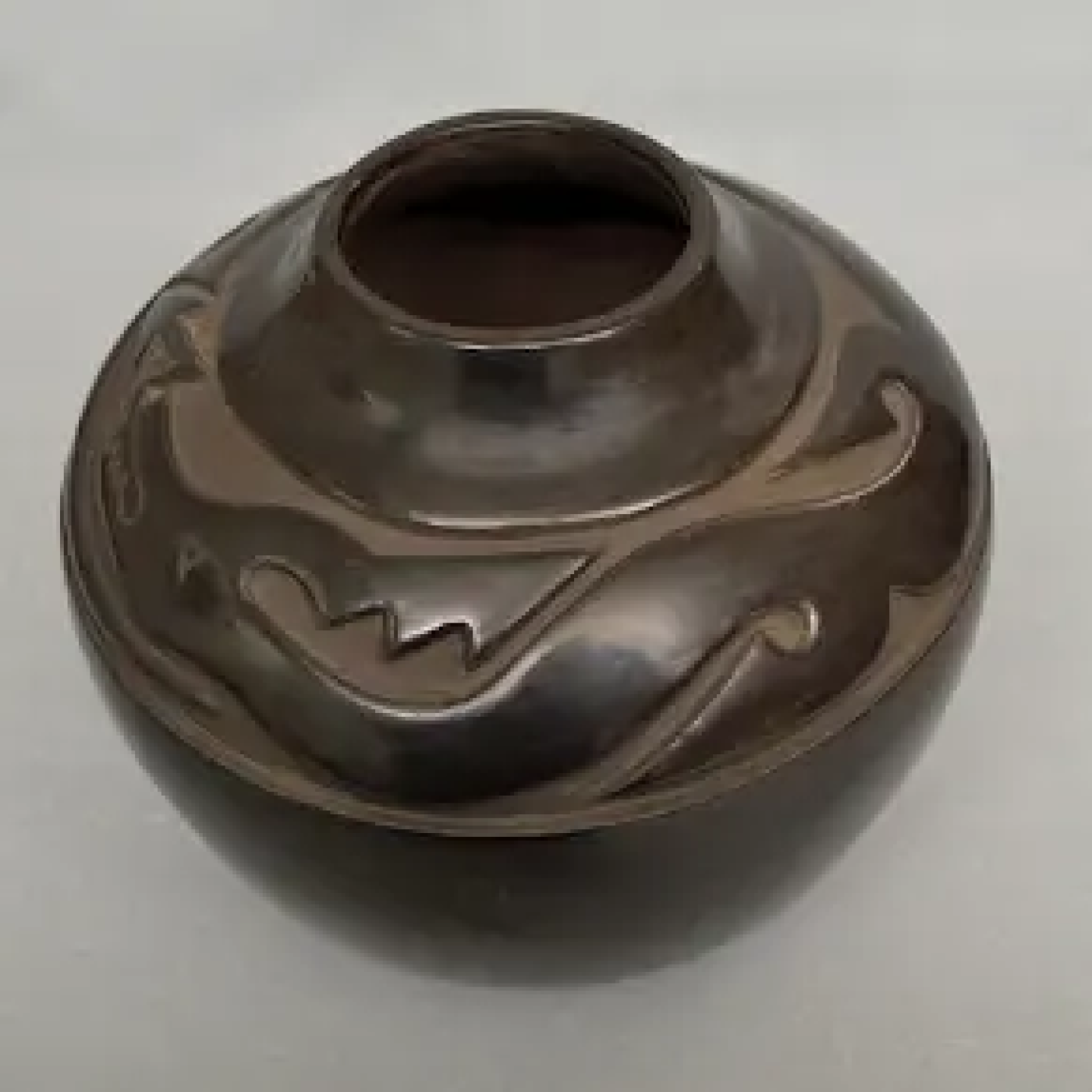 Black polished olla with carved serpent design by Margaret Tafoya. From the BIA Museum collection.